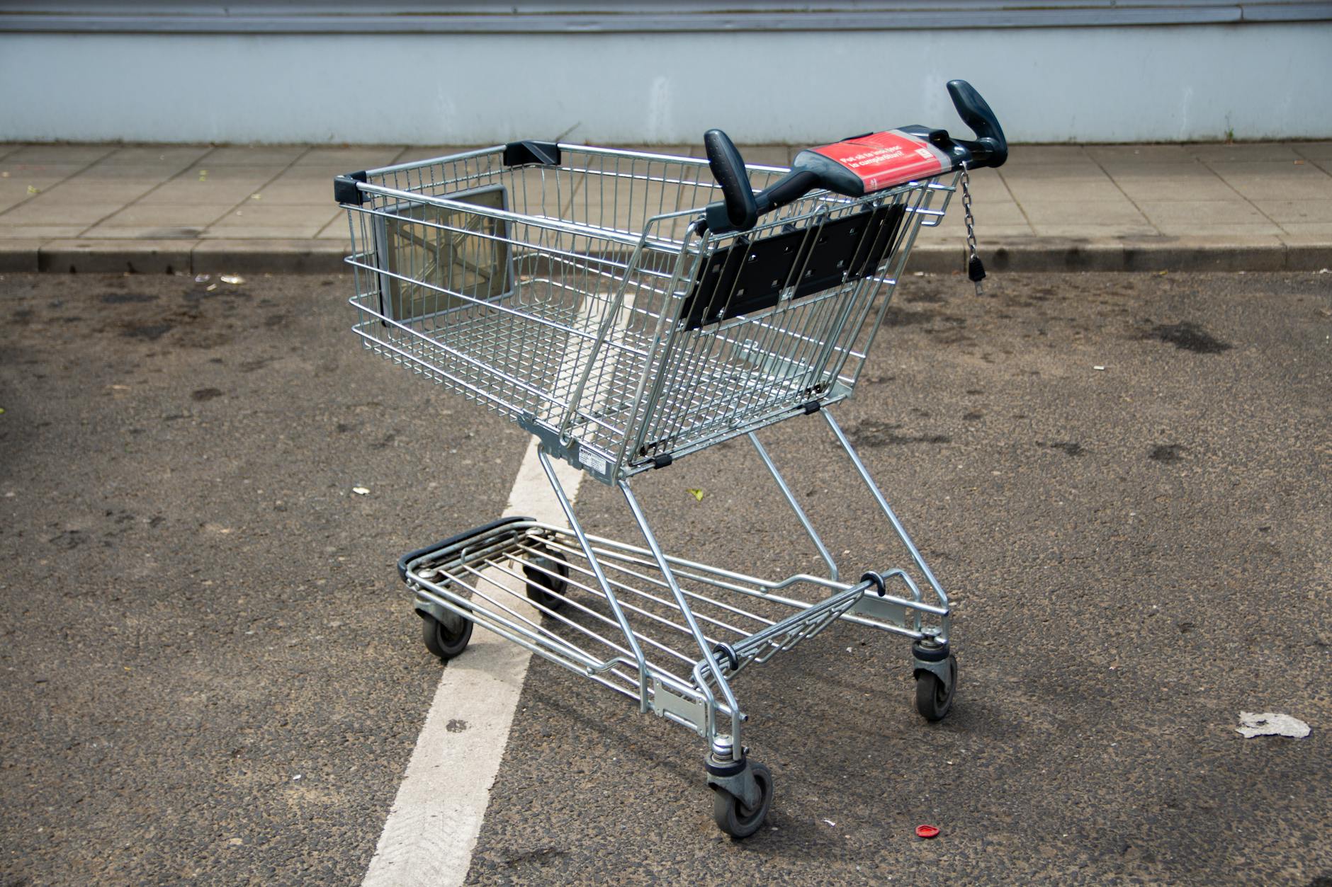 Pusty metalowy wózek sklepowy na linii na parkingu przed sklepem