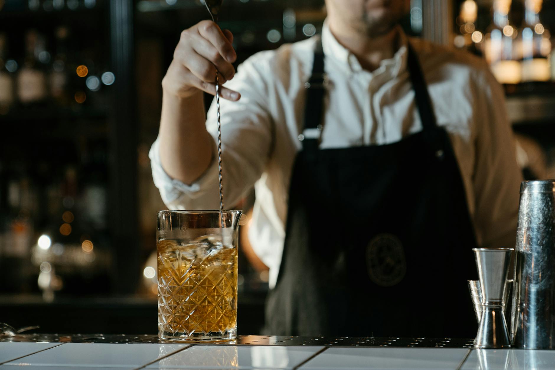 Barman w białej koszuli miesza koktajl whisky przy barze