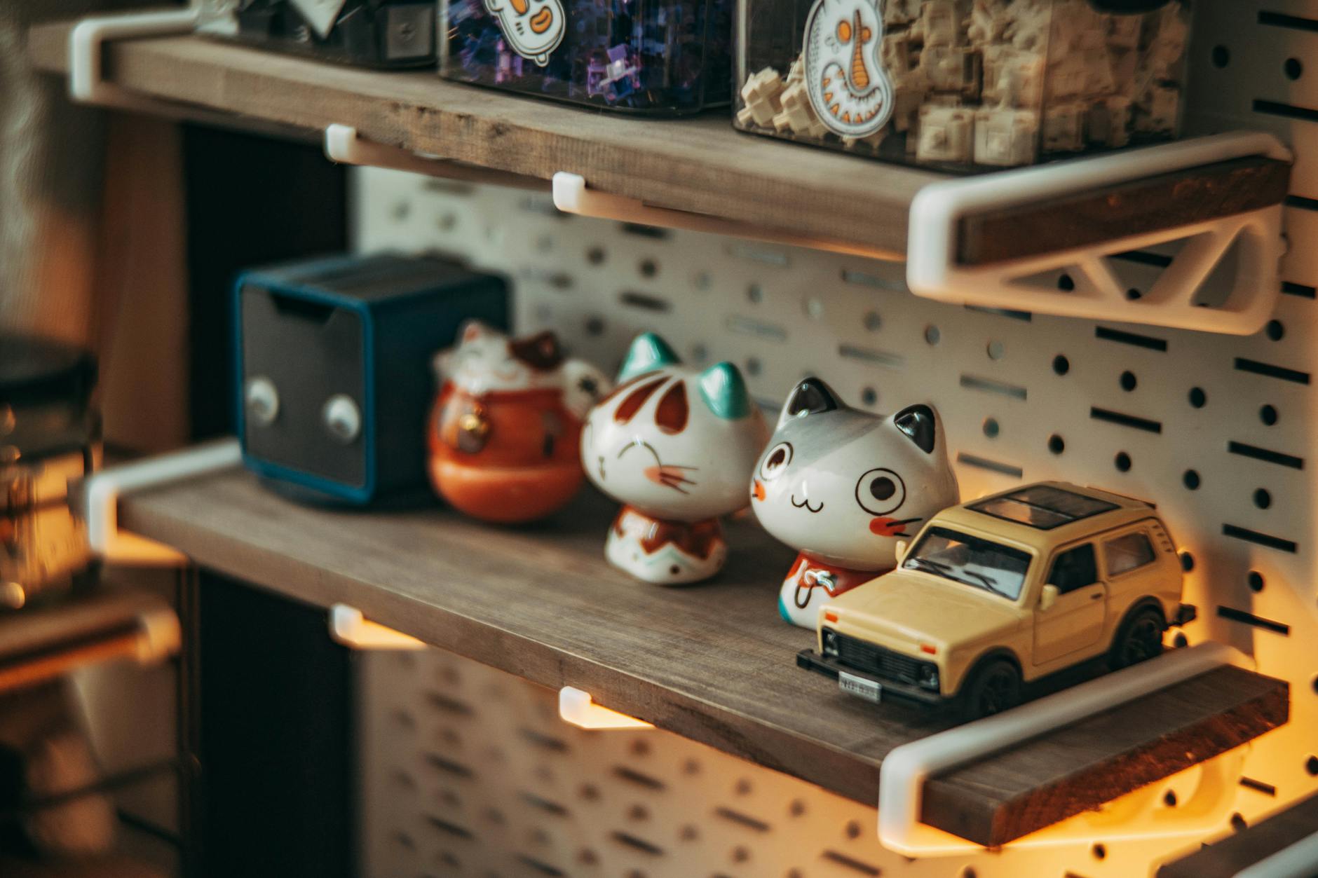 Drewniana półka z figurkami kotów i małym samochodzikiem w miękkim świetle
