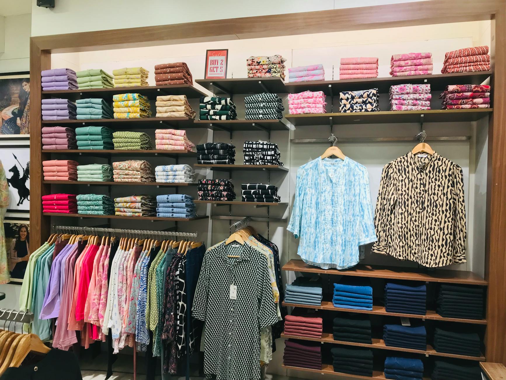 Kolorowe ubrania starannie ułożone na stojakach w sklepie odzieżowym