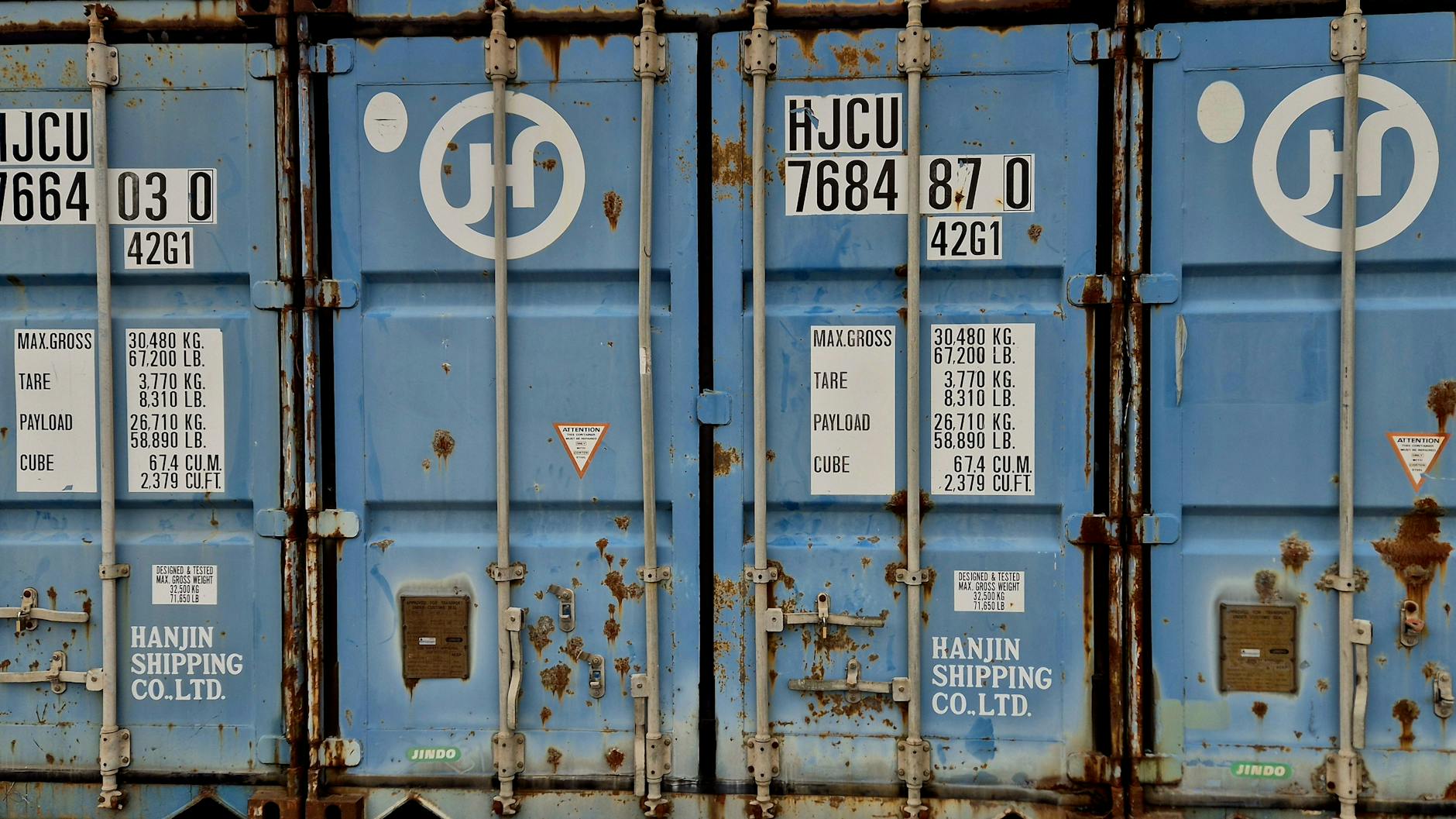 Zardzewiały niebieski kontener z widocznymi oznaczeniami udźwigu