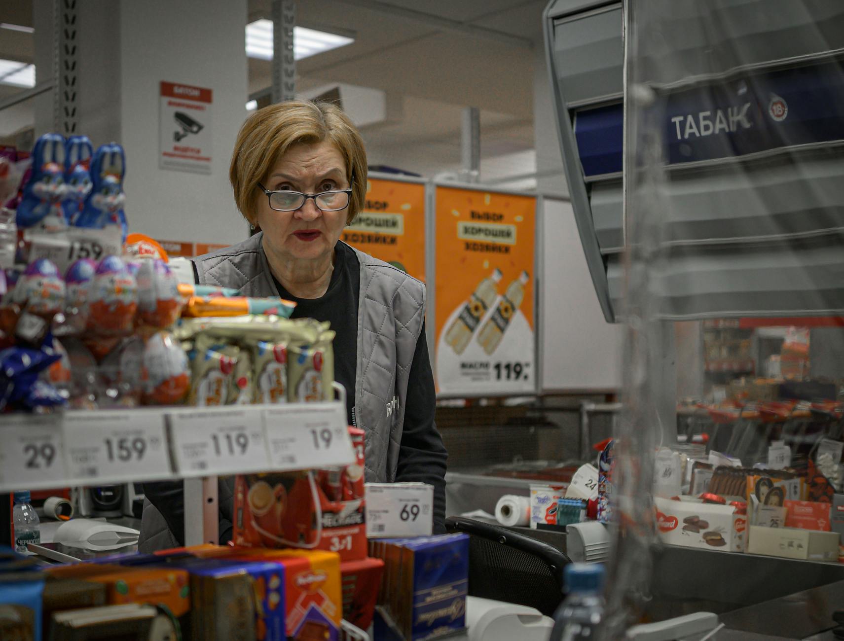 Kasjerka przy ladzie w supermarkecie z produktami na stole kasowym