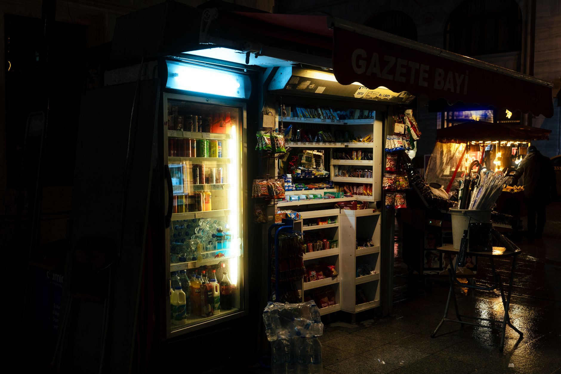 Oświetlony nocą kiosk uliczny z napojami i przekąskami
